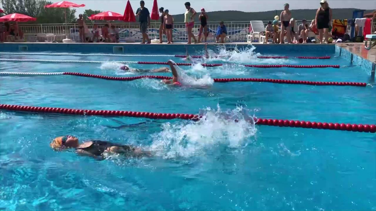 Children swimming while campers and supervisors gather beside the pool at Sea Dunes International Children's Camp